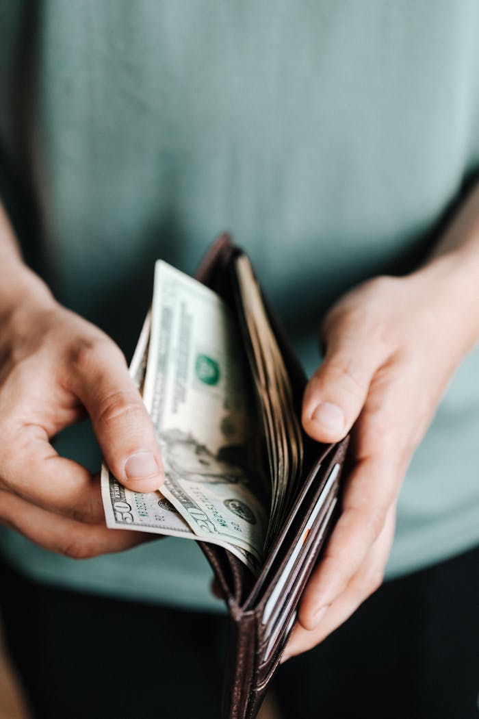 about-us Close-up of hands holding a wallet with cash, depicting financial management.